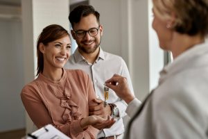 happy-couple-buying-their-new-home-receiving-keys-from-real-estate-agent